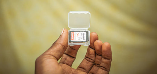 Close-up image of a hand holding a SanDisk Ultra PLUS 64GB memory card in a transparent protective case.